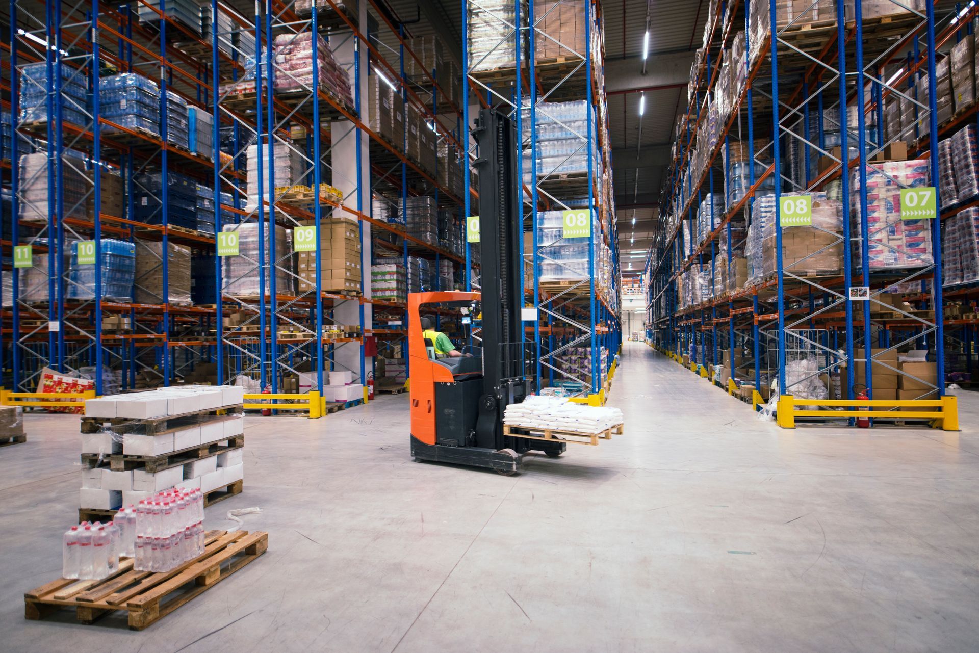 A forklift is moving a pallet in a large warehouse.