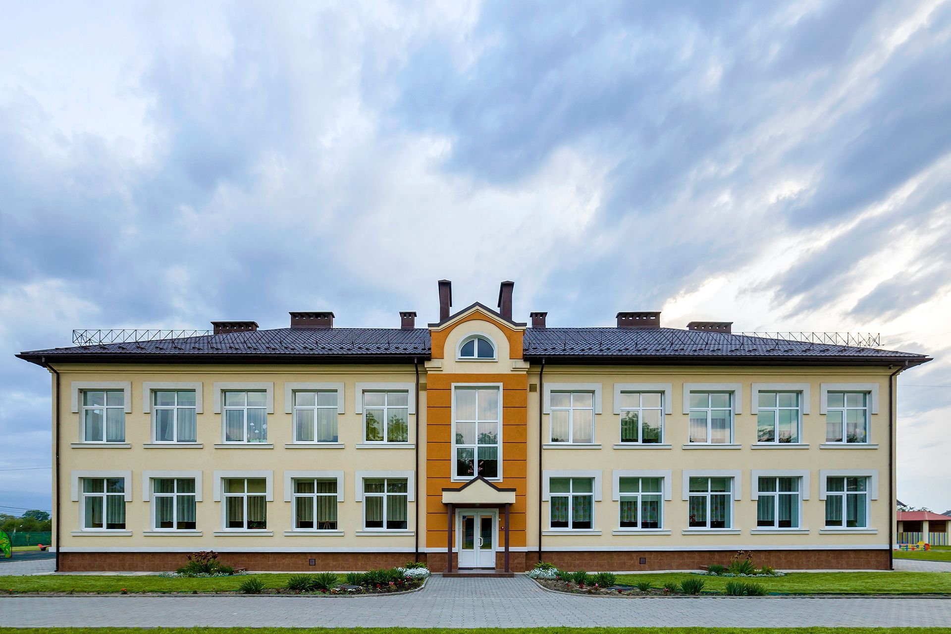 A large building with a lot of windows and a cloudy sky in the background.