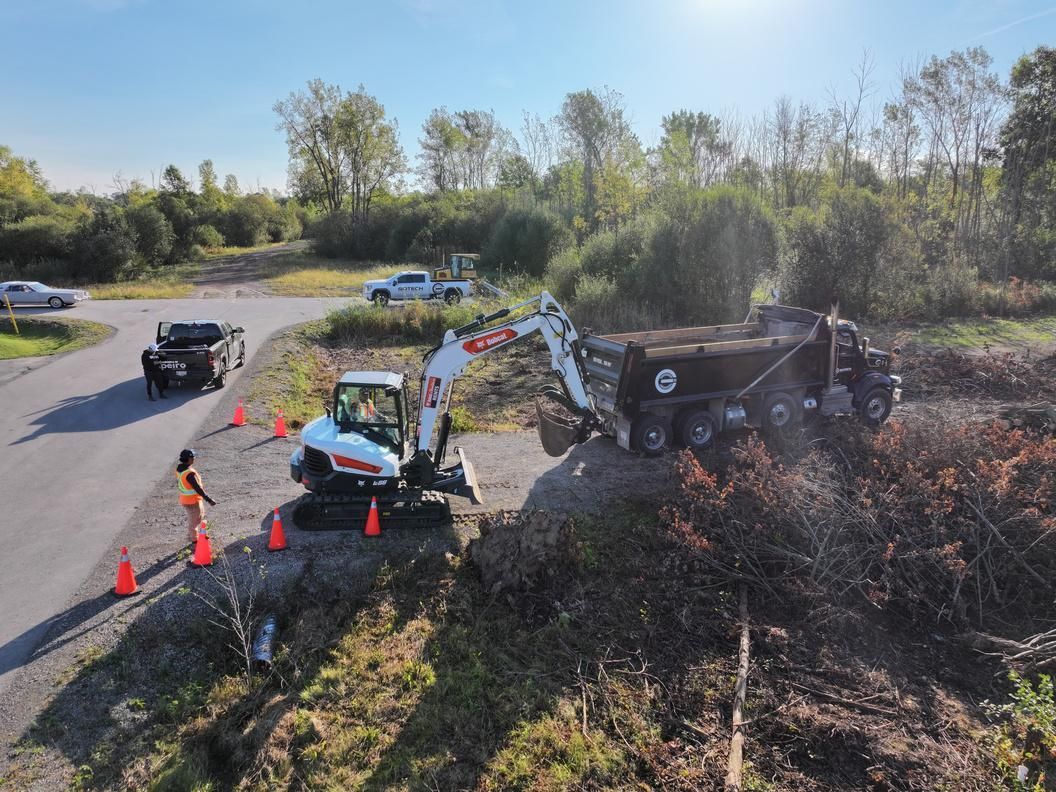 Emergency response vehicles and cones at a roadside crash scene beside a ditch and overturned truck.