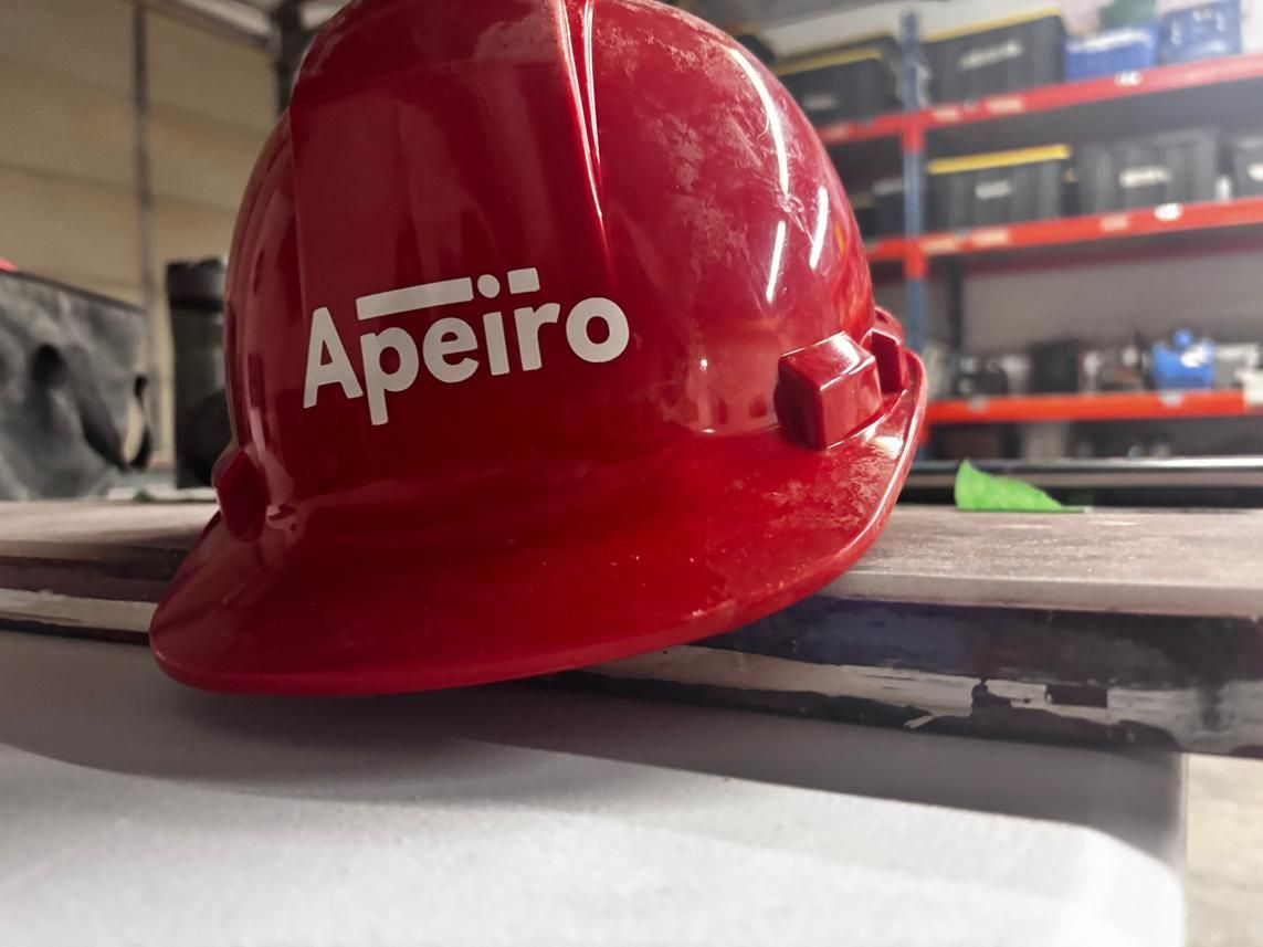 Red Apeiro hard hat resting on a workbench in a warehouse setting