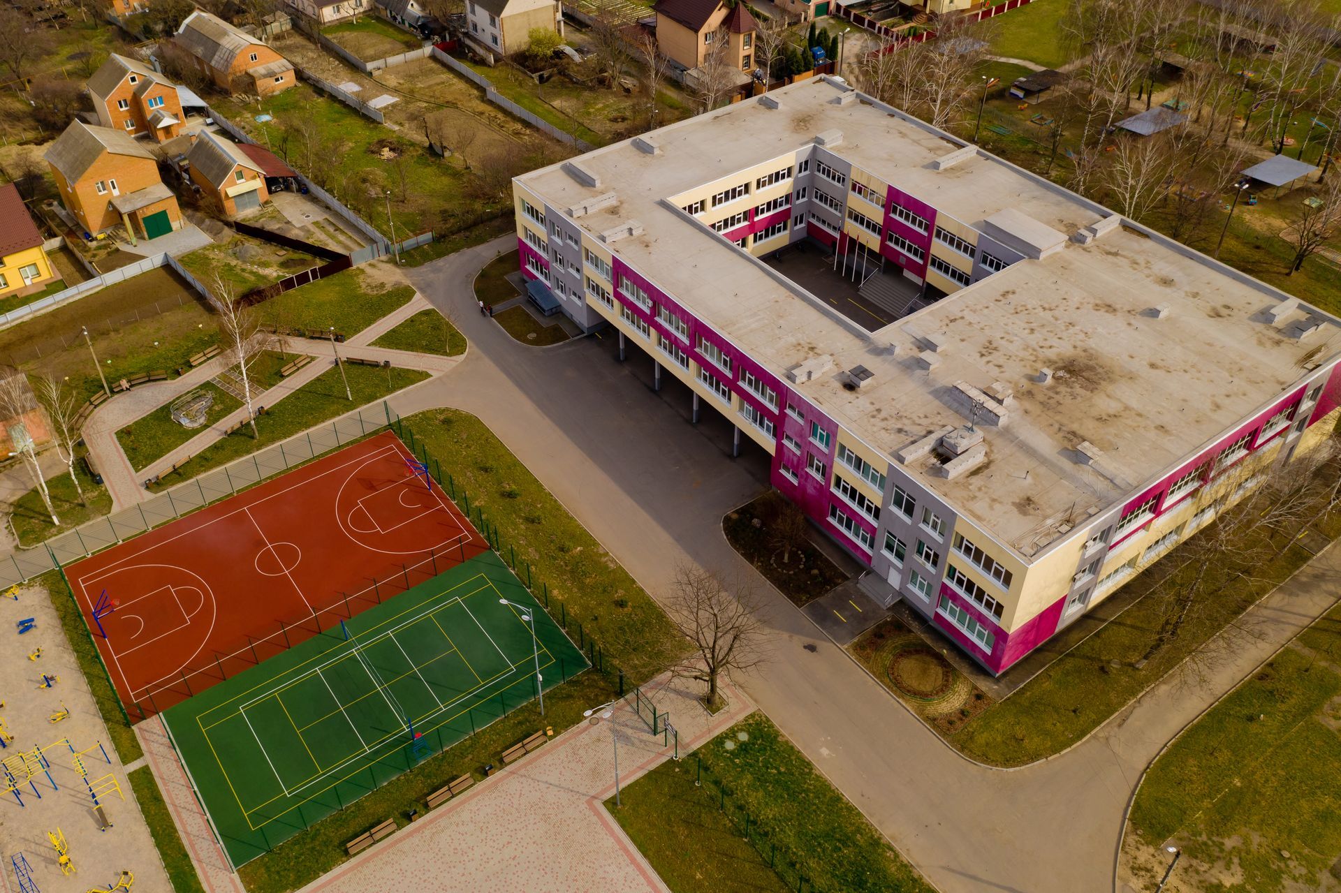 An aerial view of a large building with a tennis court in front of it.