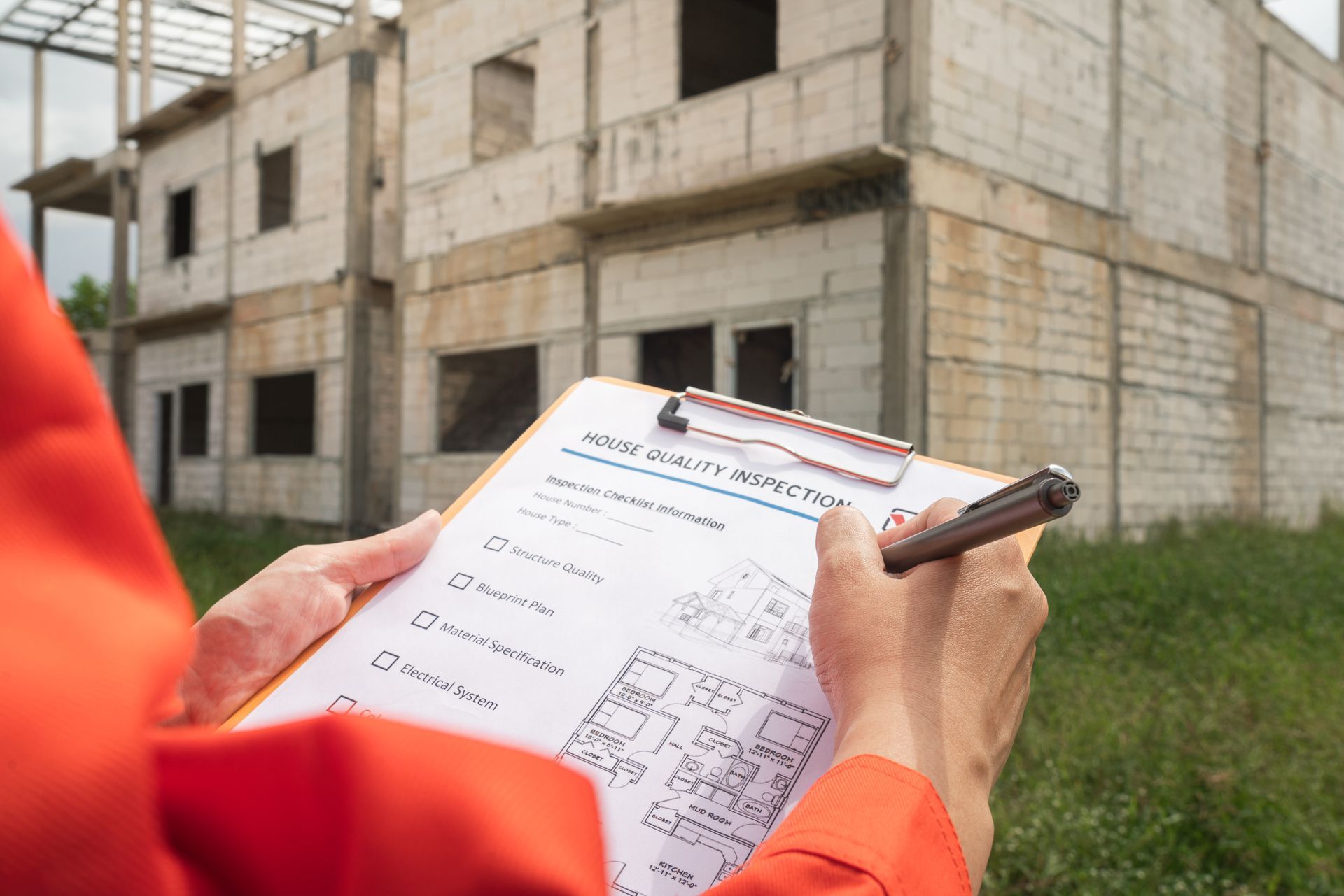 A person is holding a clipboard and a pen in front of a building under construction.