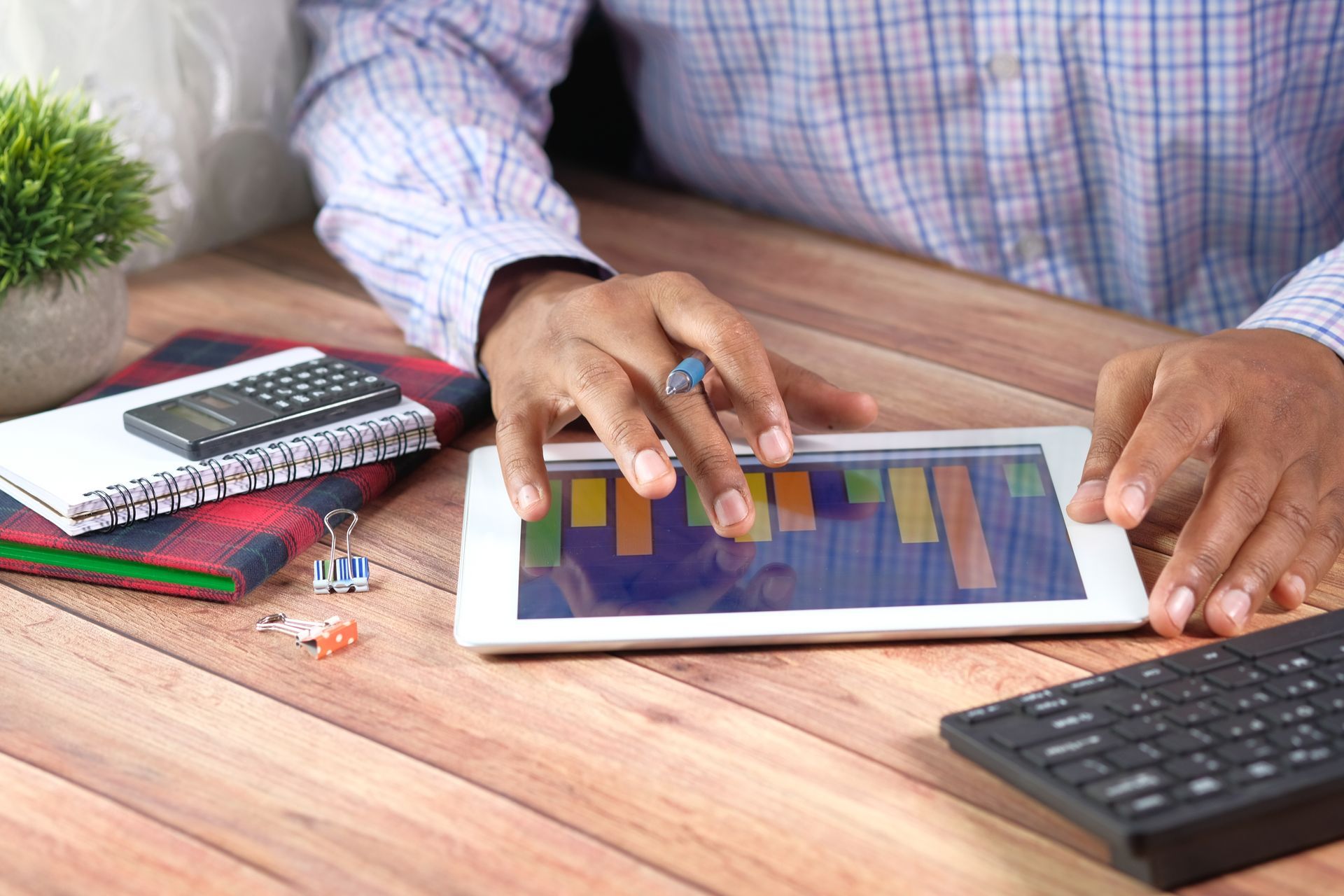 A man is sitting at a table using a tablet computer.