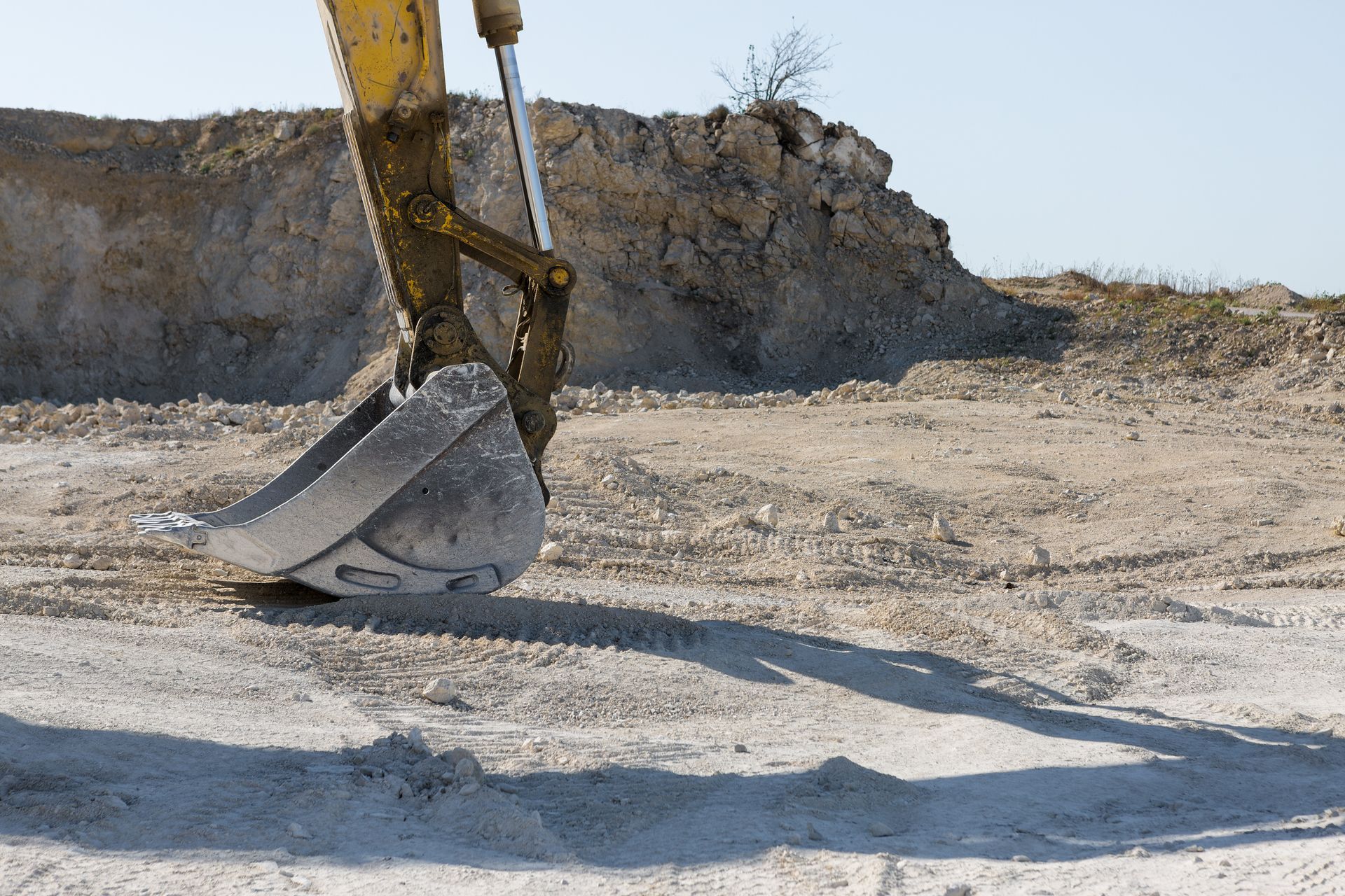 A yellow excavator is digging a hole in the dirt.