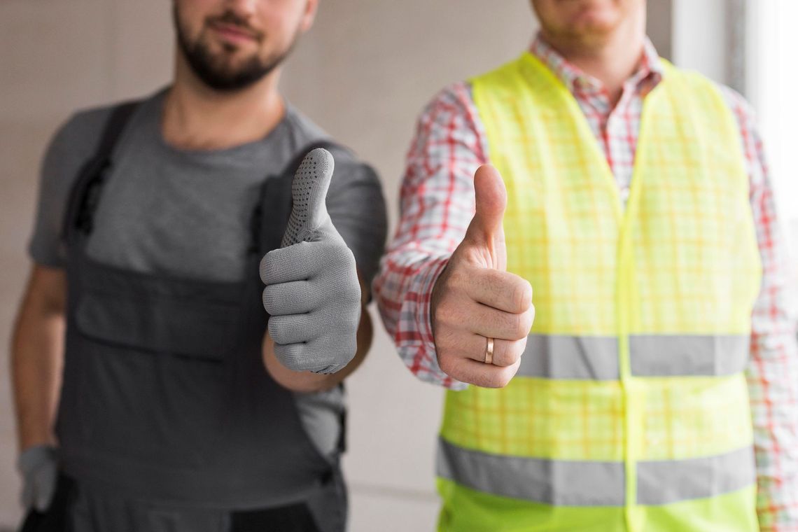 Two construction workers are giving a thumbs up sign.