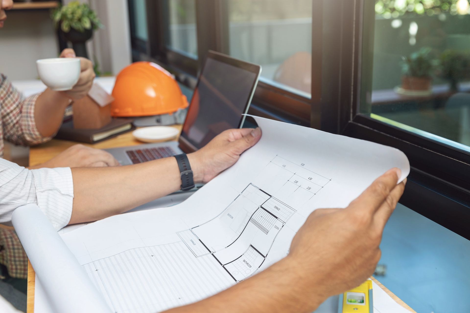 Two men are sitting at a table looking at a blueprint.