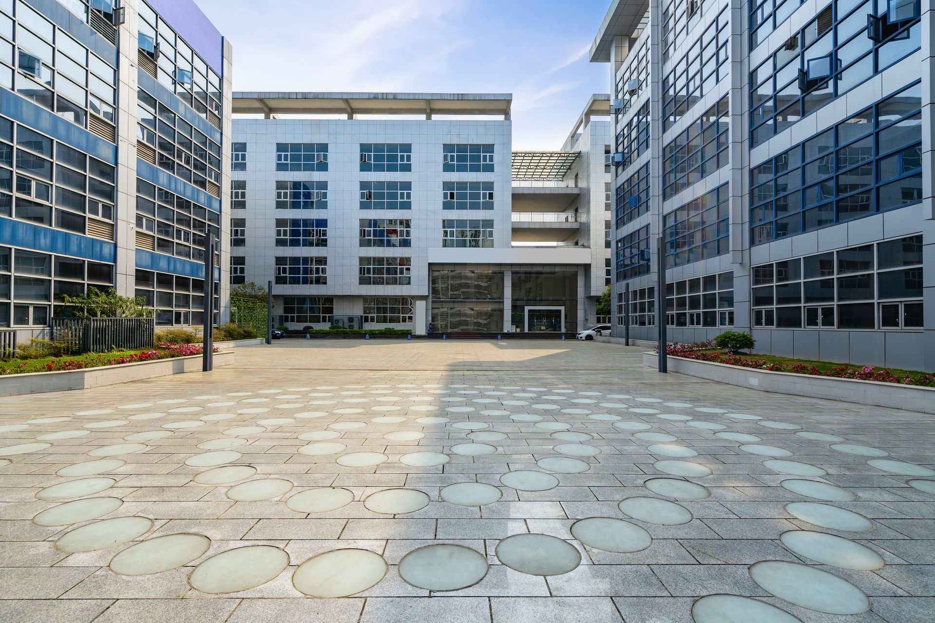A large building with a lot of windows and a brick walkway in front of it.