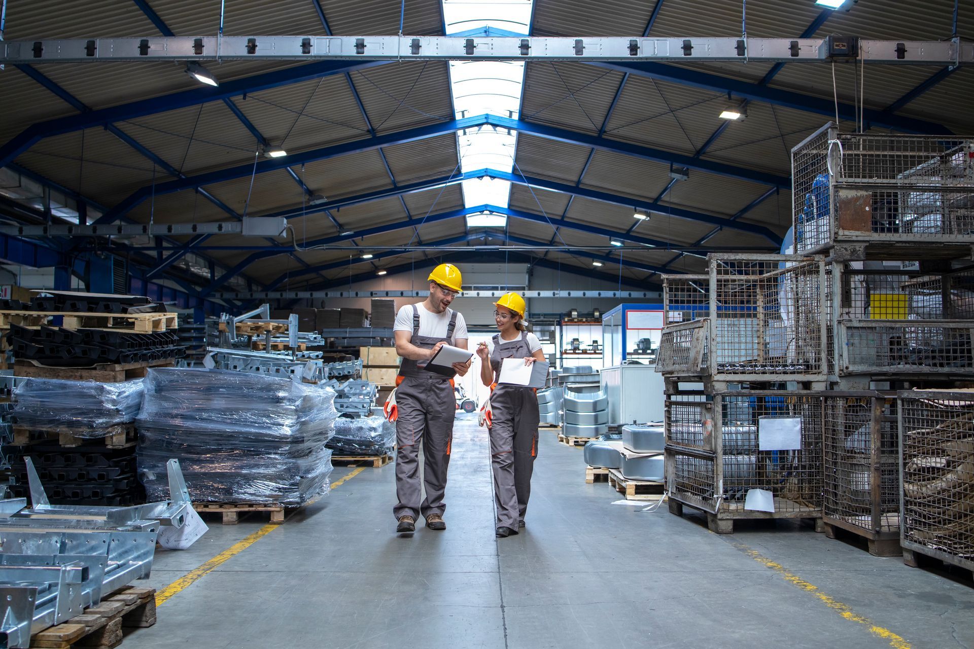 Two workers are walking through a warehouse looking at a tablet.
