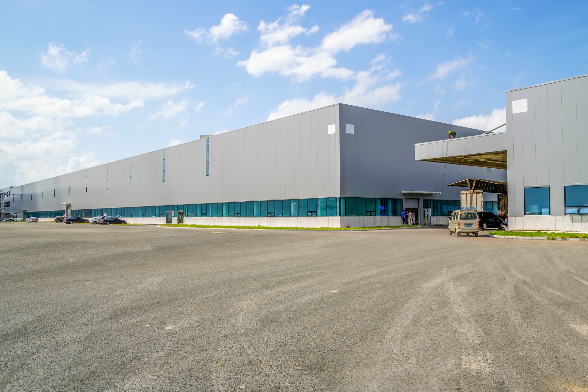 A large warehouse with a lot of windows and a truck parked in front of it.