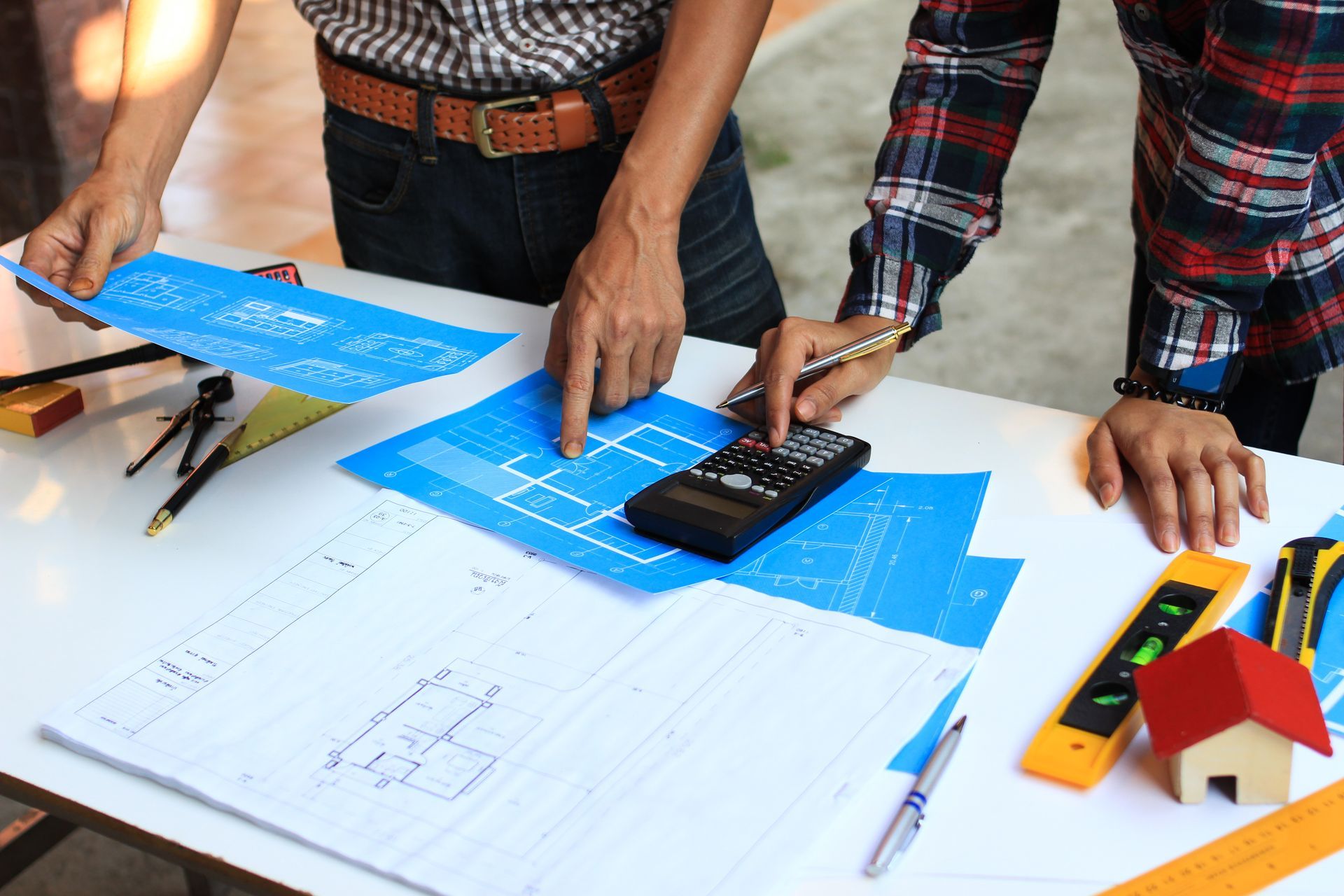 Two men are working on a blueprint of a house.