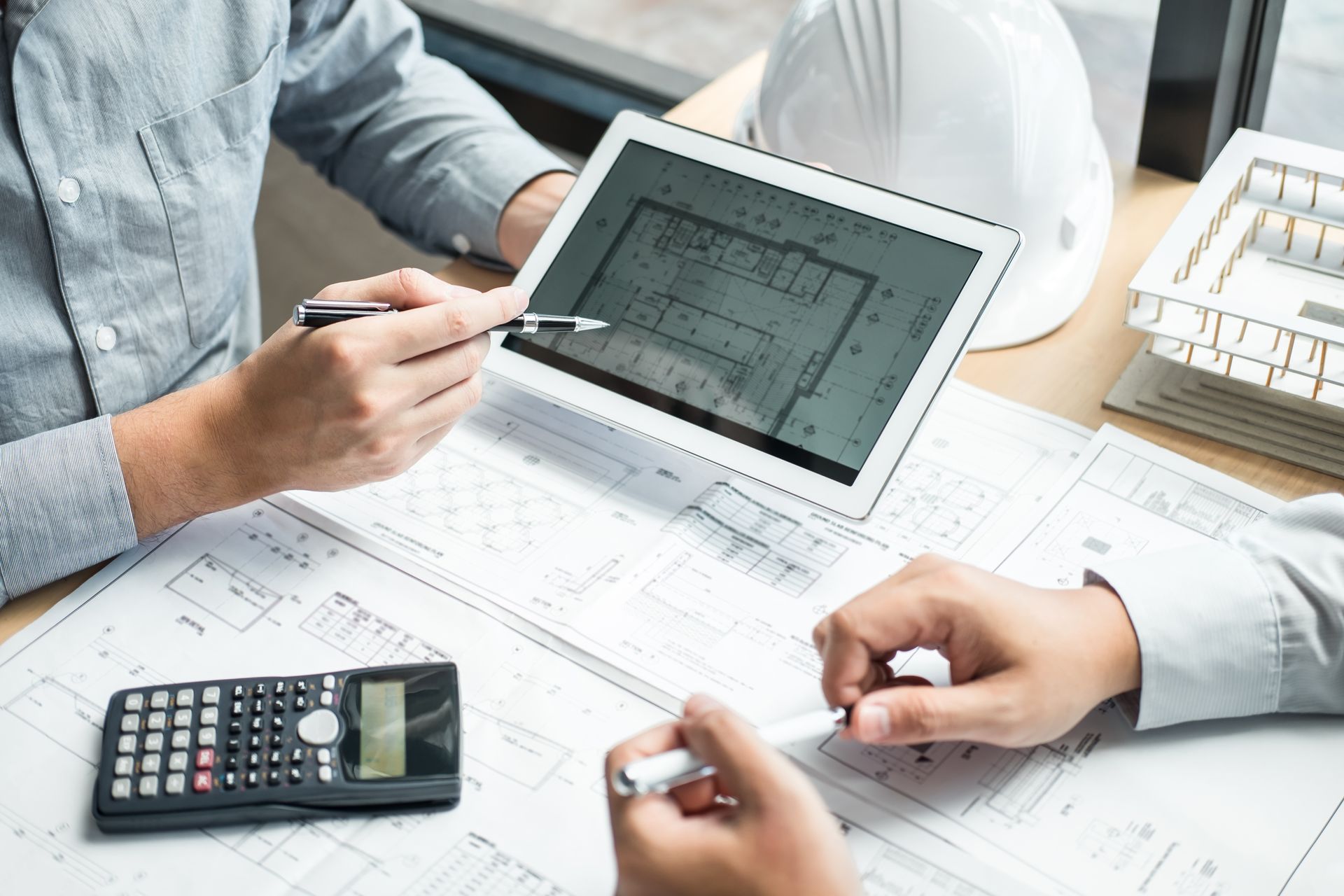 Two men are sitting at a table looking at a tablet.