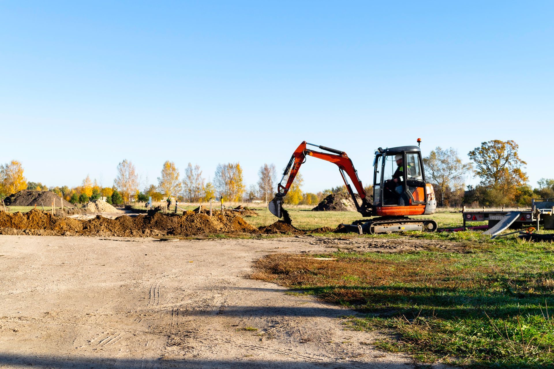 A small excavator is digging a hole in a dirt field.