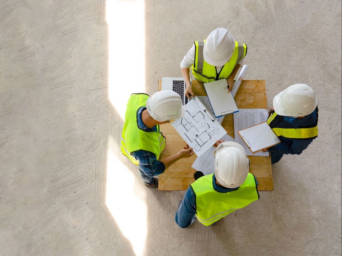 A group of construction workers are sitting around a table looking at a blueprint.