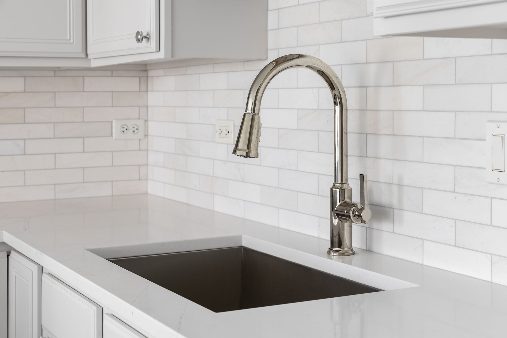 A kitchen sink with a faucet and white cabinets