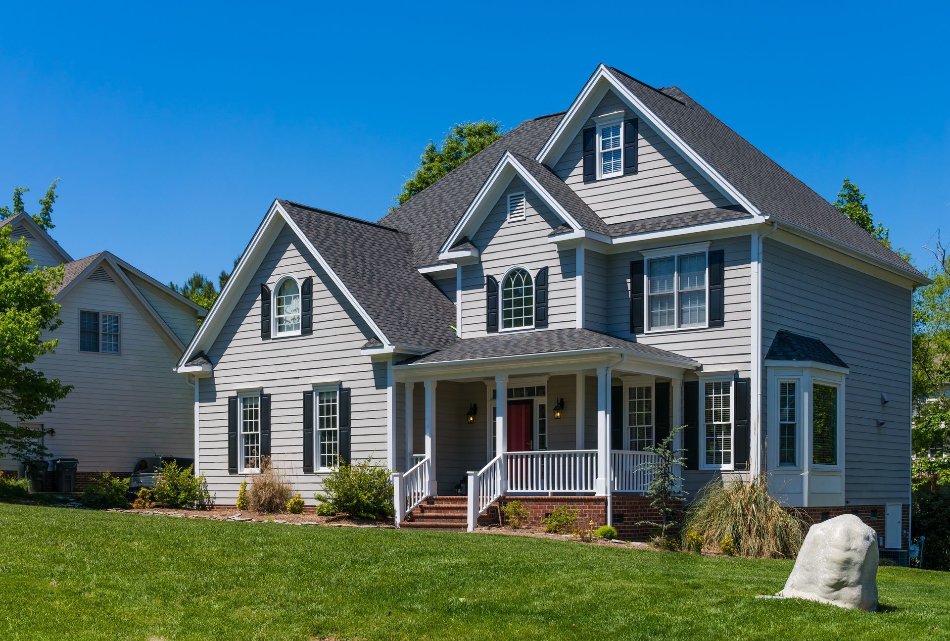 A large white house with a porch and a blue sky in the background