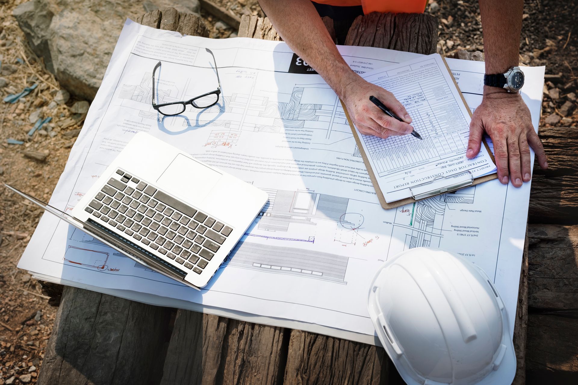 A man is sitting at a table with a laptop and a hard hat.