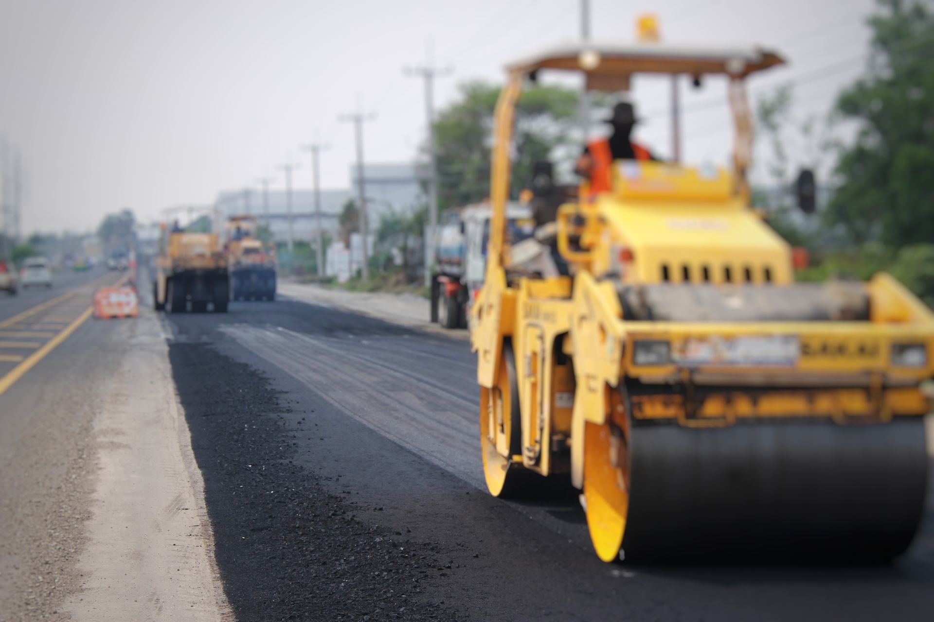 A yellow roller is rolling asphalt on a road.