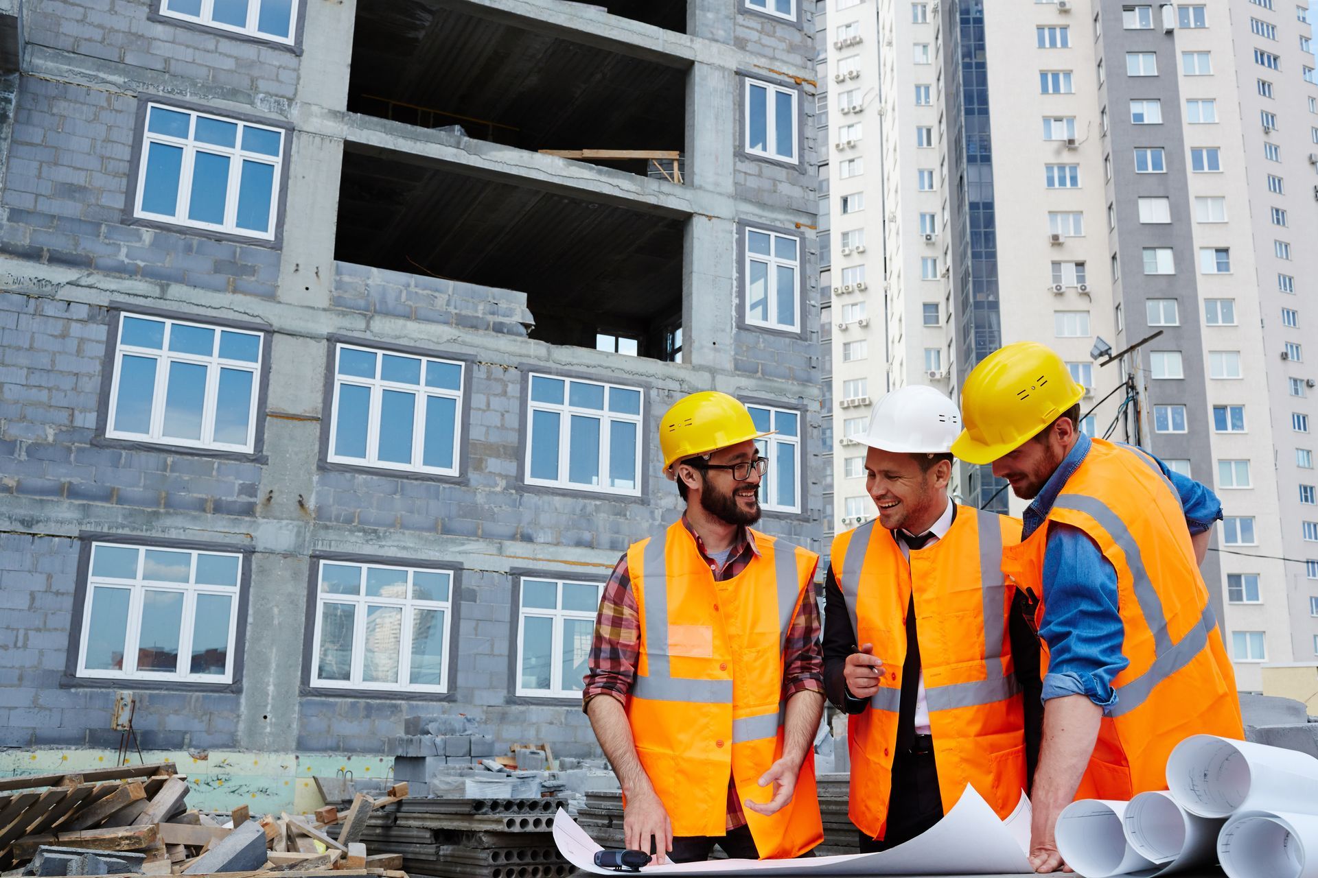 A group of construction workers are looking at a blueprint at a construction site.
