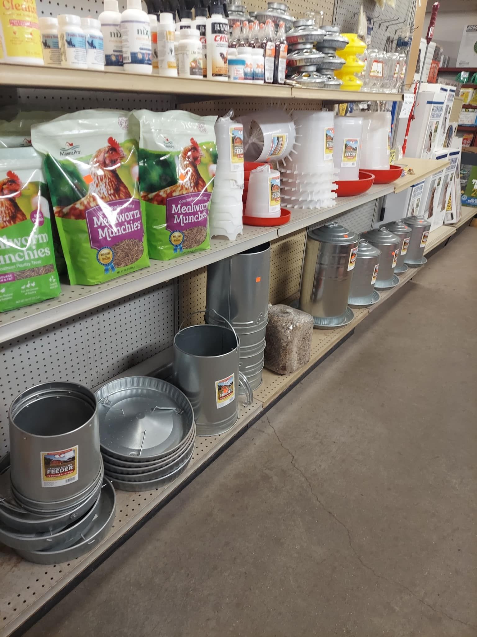 Shelves stocked with chicken feed and waterers in a store.