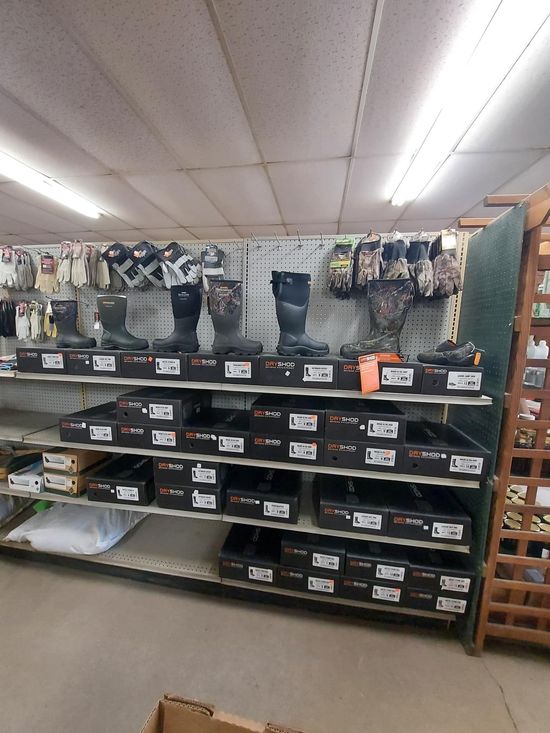 Boots and gloves displayed on store shelves. Black boxes are on lower shelves.