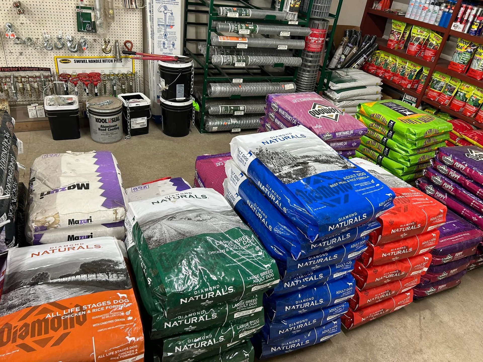 Bags of pet food, fertilizers, and hardware in a store. Several colors and brands are visible.