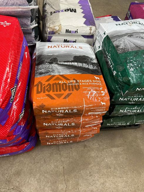 Stacked orange and white bags of Diamond Naturals dog food in a store.