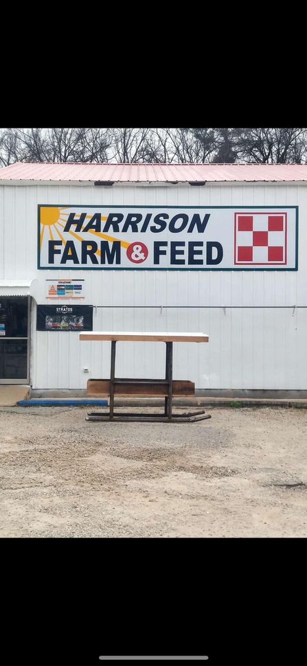 Harrison Farm & Feed store sign, with a picnic table in front.