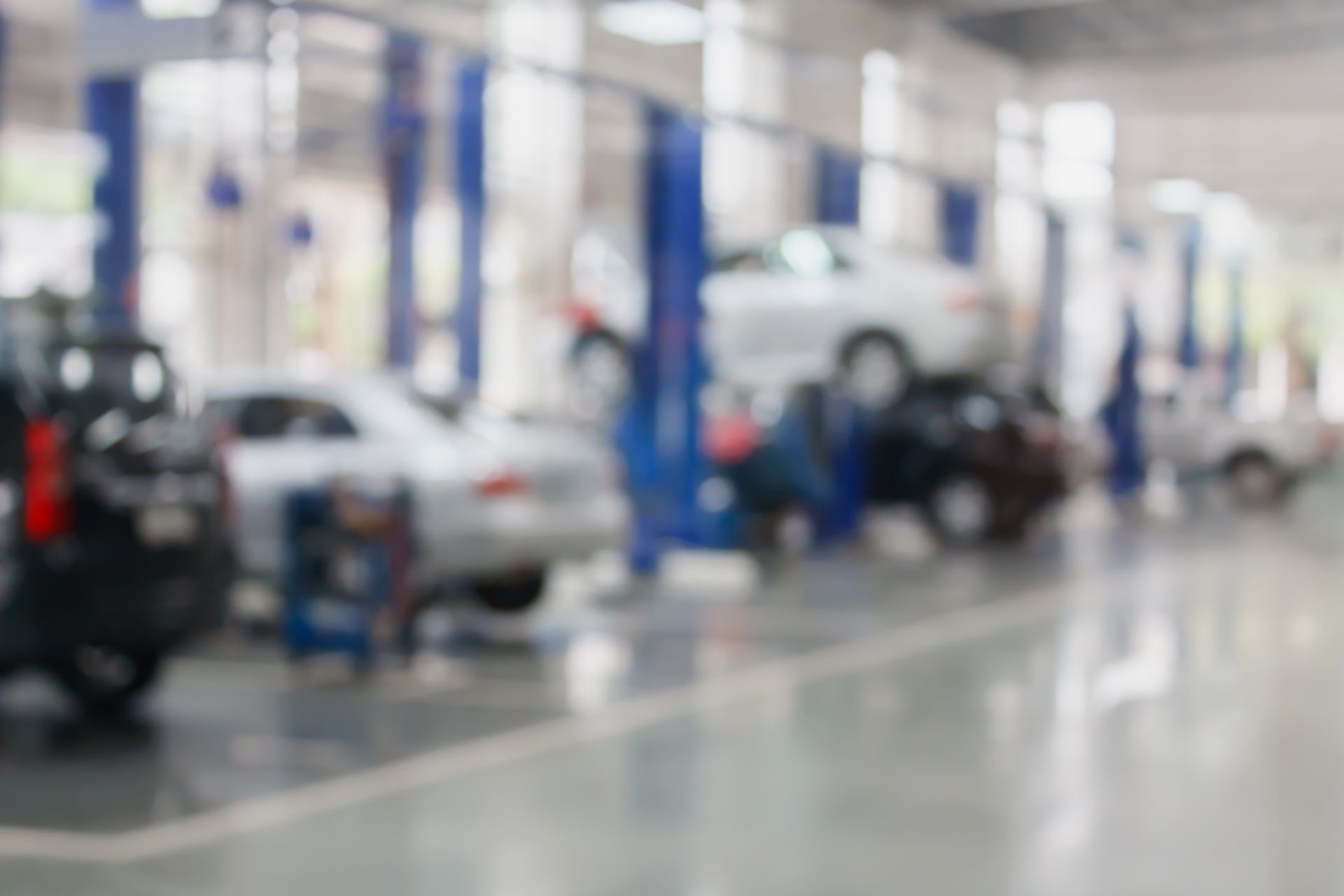 A blurred auto repair shop interior with cars on lifts and mechanics working A blurred auto repair shop interior with cars on lifts and mechanics working