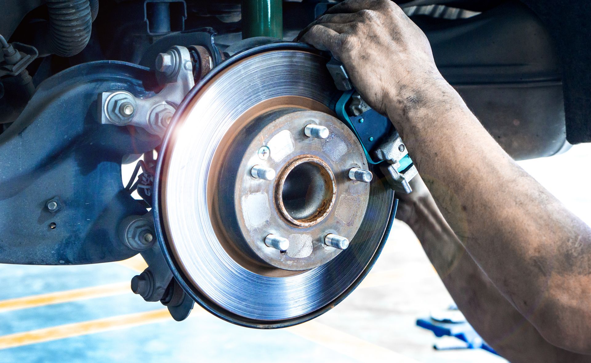 Close-up of hands installing a brake caliper on a car's disc brake.