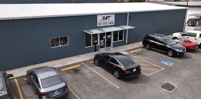 Exterior of a business with a blue facade, parking spaces, and cars parked in front.