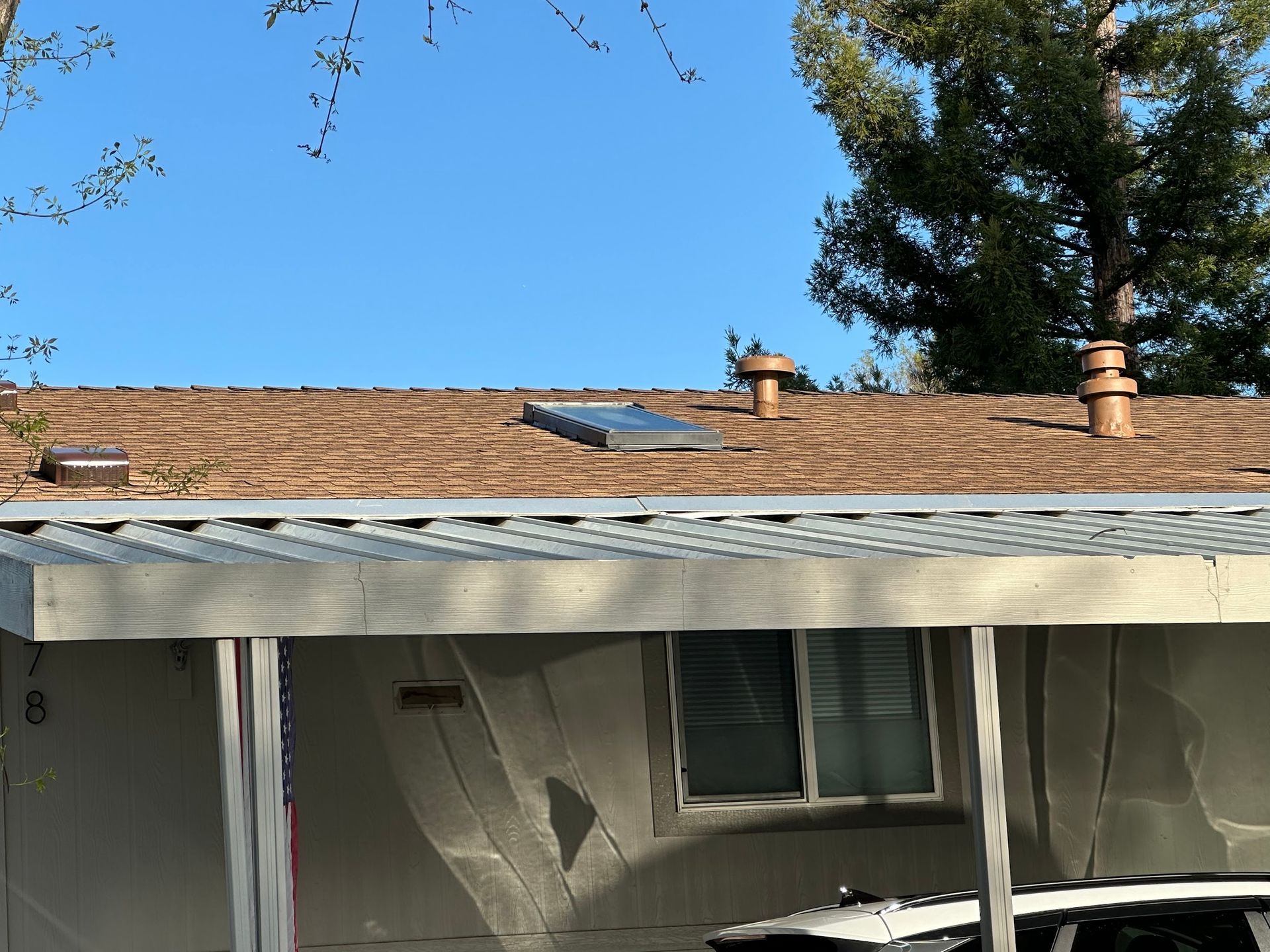 A house with a carport and a roof with a skylight