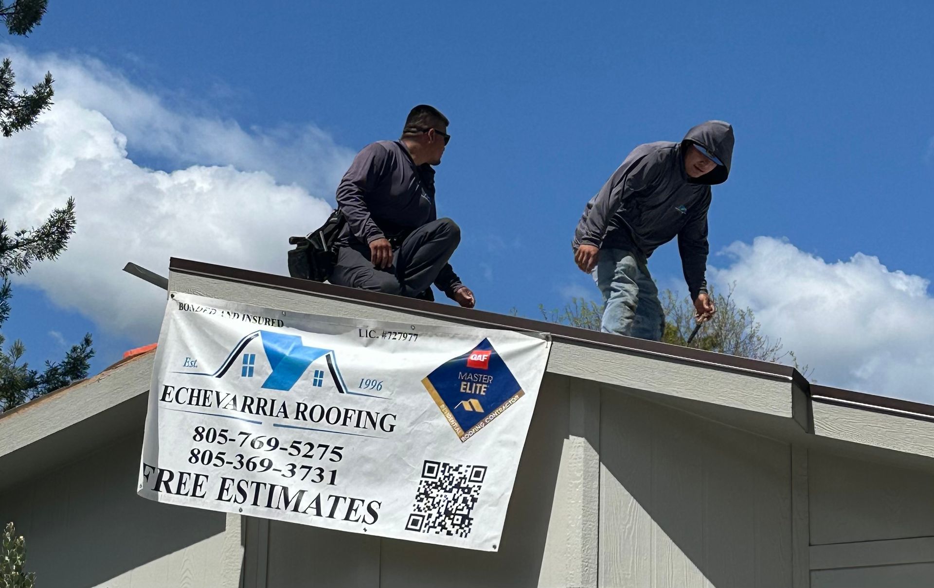 Two men are working on the roof of a house.