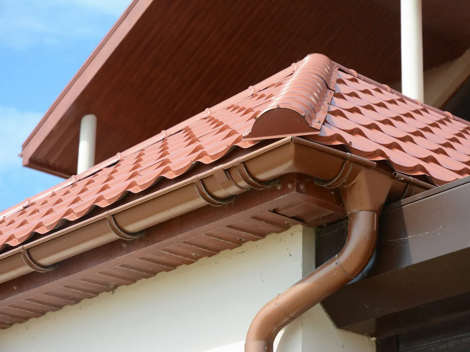 A gutter on the side of a house with a red tile roof
