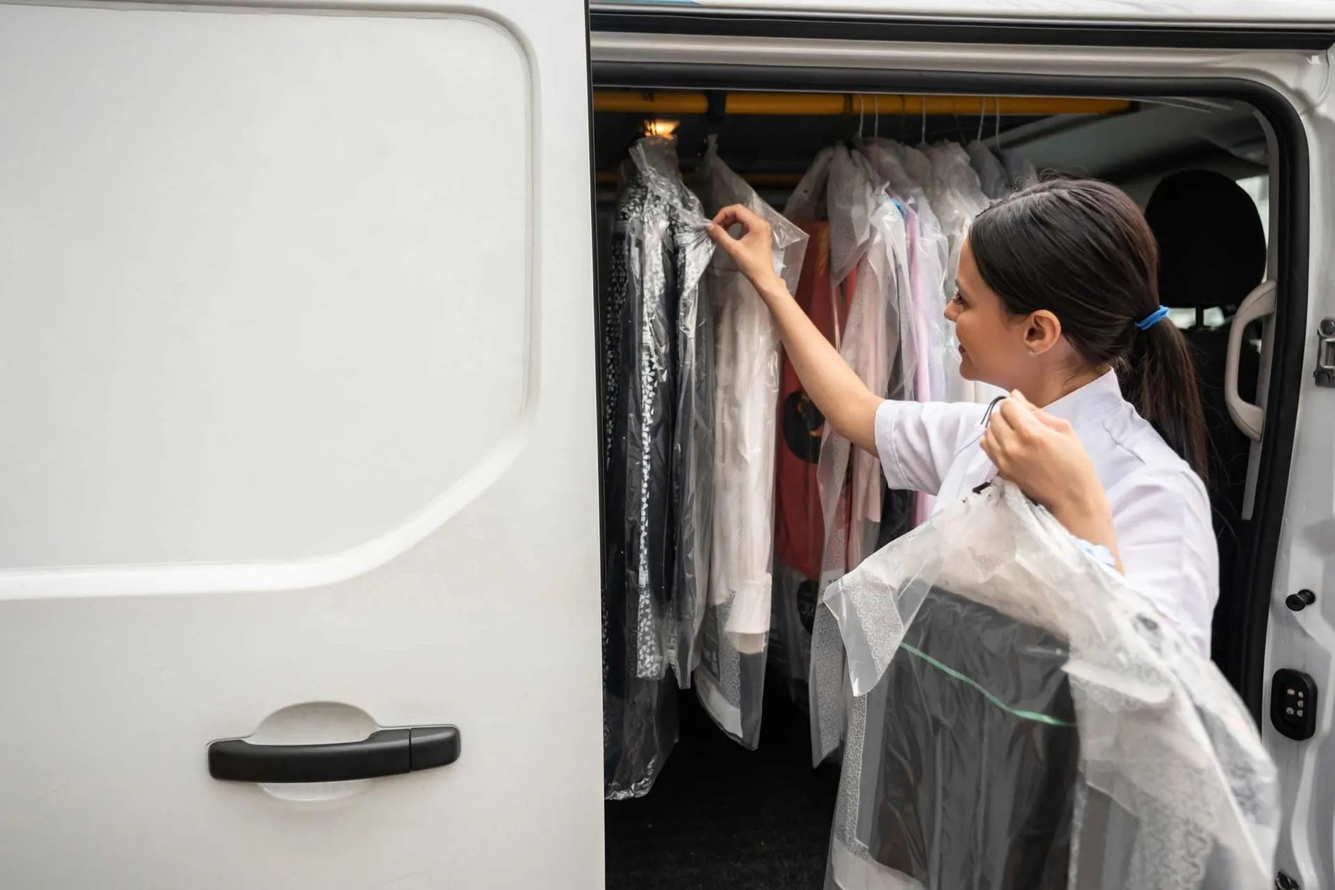 a woman is putting clothes in the back of a van