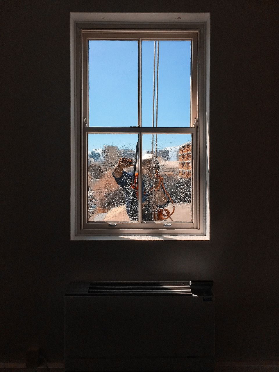 a window in a dark room with a blue sky behind it