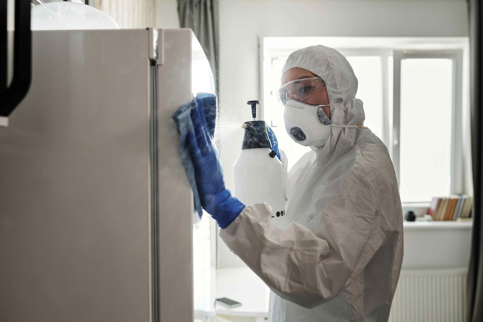 a man in a protective suit is cleaning a refrigerator