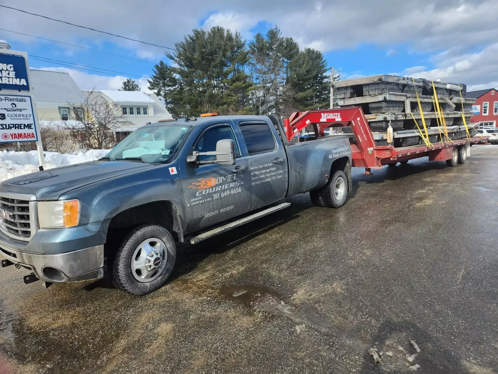 A truck is towing a trailer with a crane attached to it.