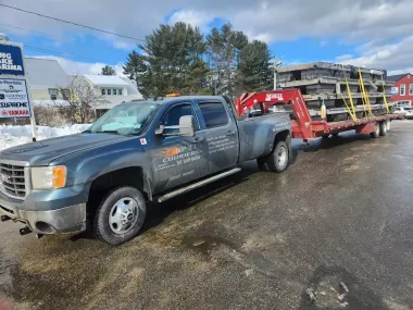 A truck is towing a trailer with a crane attached to it.