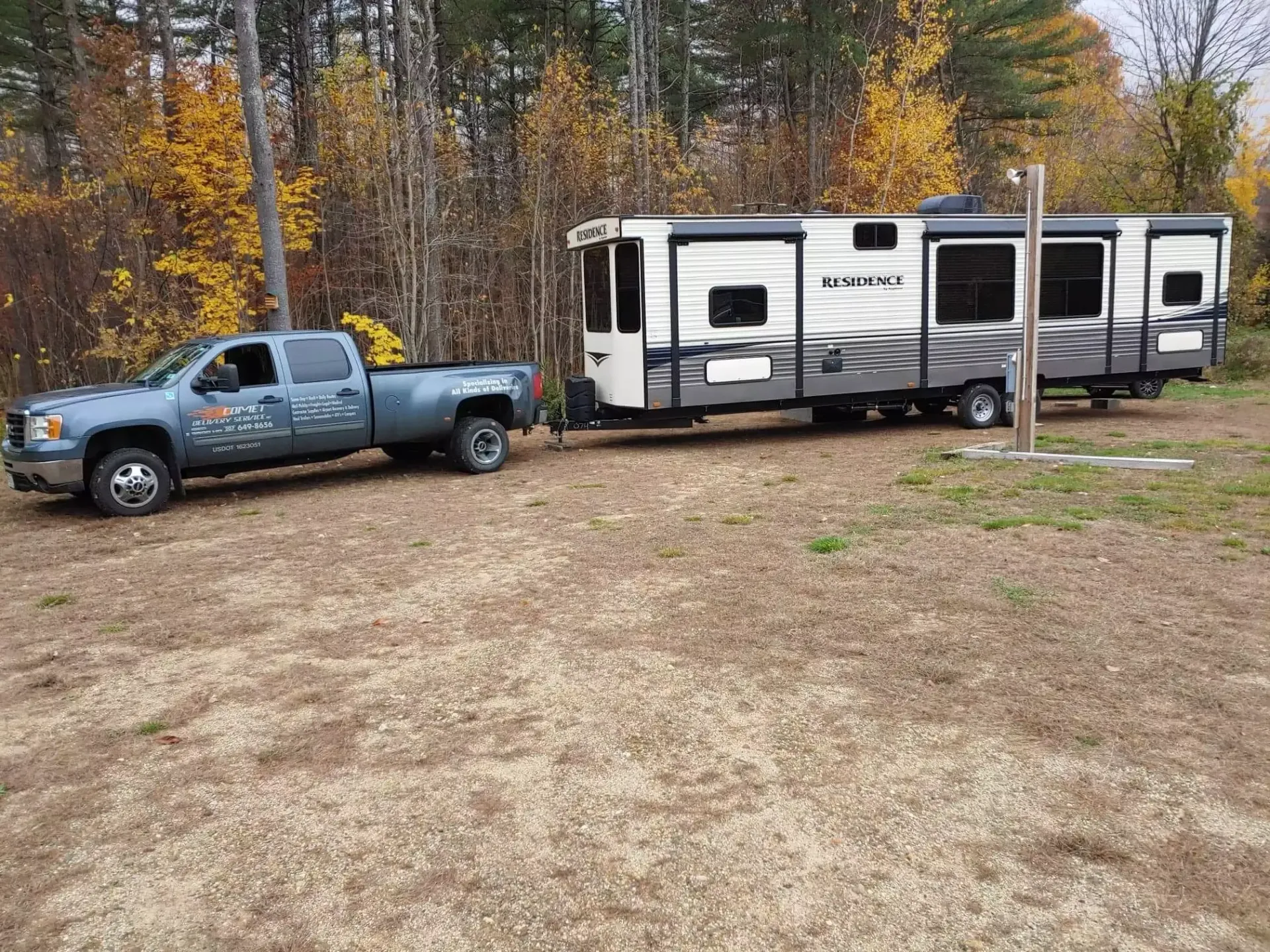 A truck is towing a trailer in a dirt field.
