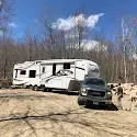 A rv is parked in a dirt lot next to a truck.