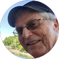 A man wearing glasses and a baseball cap is smiling in a circle.