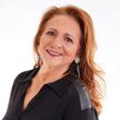 A woman with red hair is wearing a black shirt and earrings