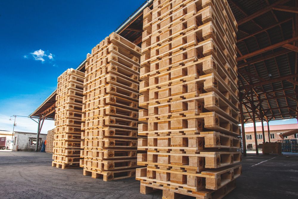 A warehouse filled with lots of wooden pallets stacked on top of each other.