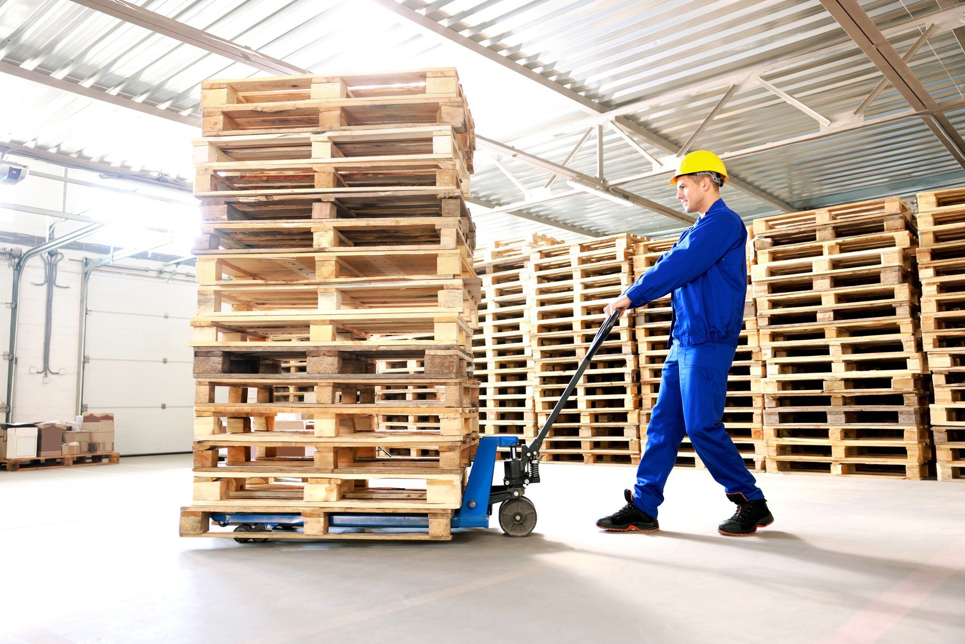 a man is pushing a cart full of wooden pallets showing pallet stacking