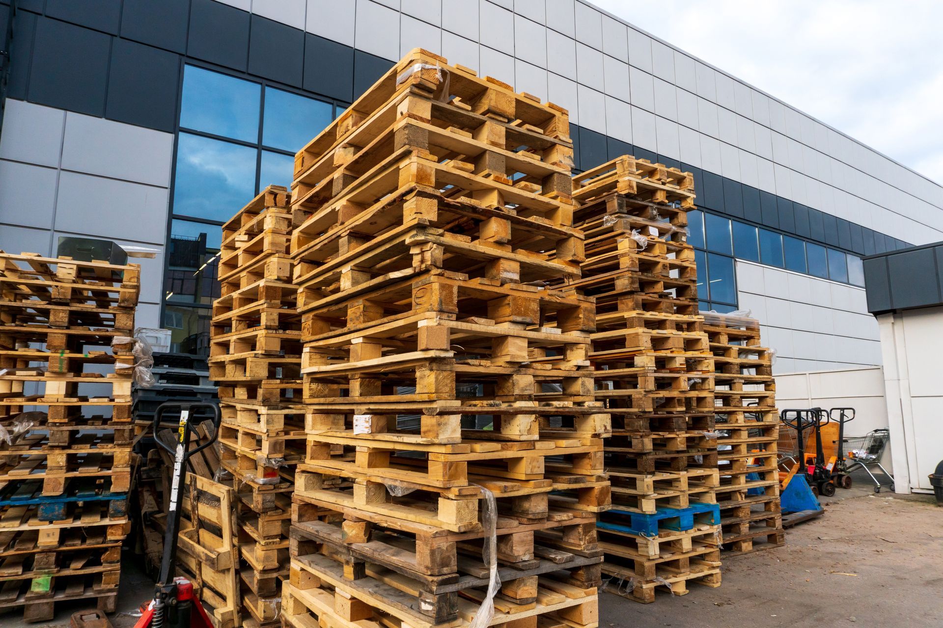 stacks of various types of wooden shipping pallets in front of a building.