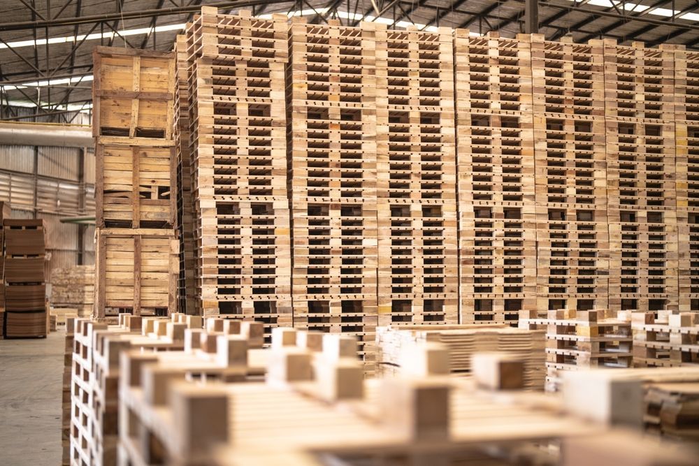 A warehouse filled with lots of wooden pallets stacked on top of each other.