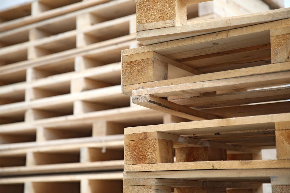 A pile of wooden pallets & skids stacked on top of each other.