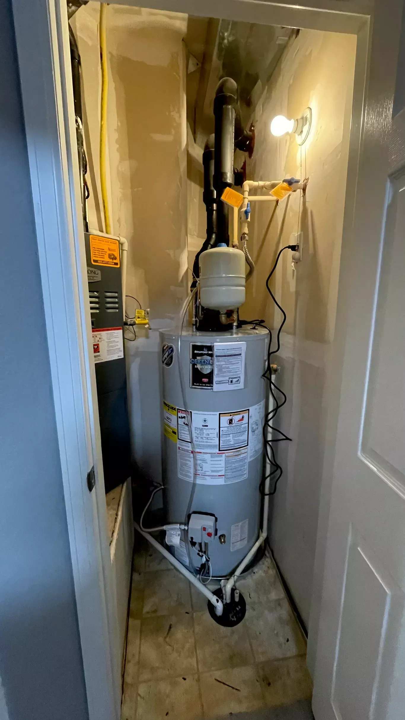 A water heater is sitting in a closet next to a door.