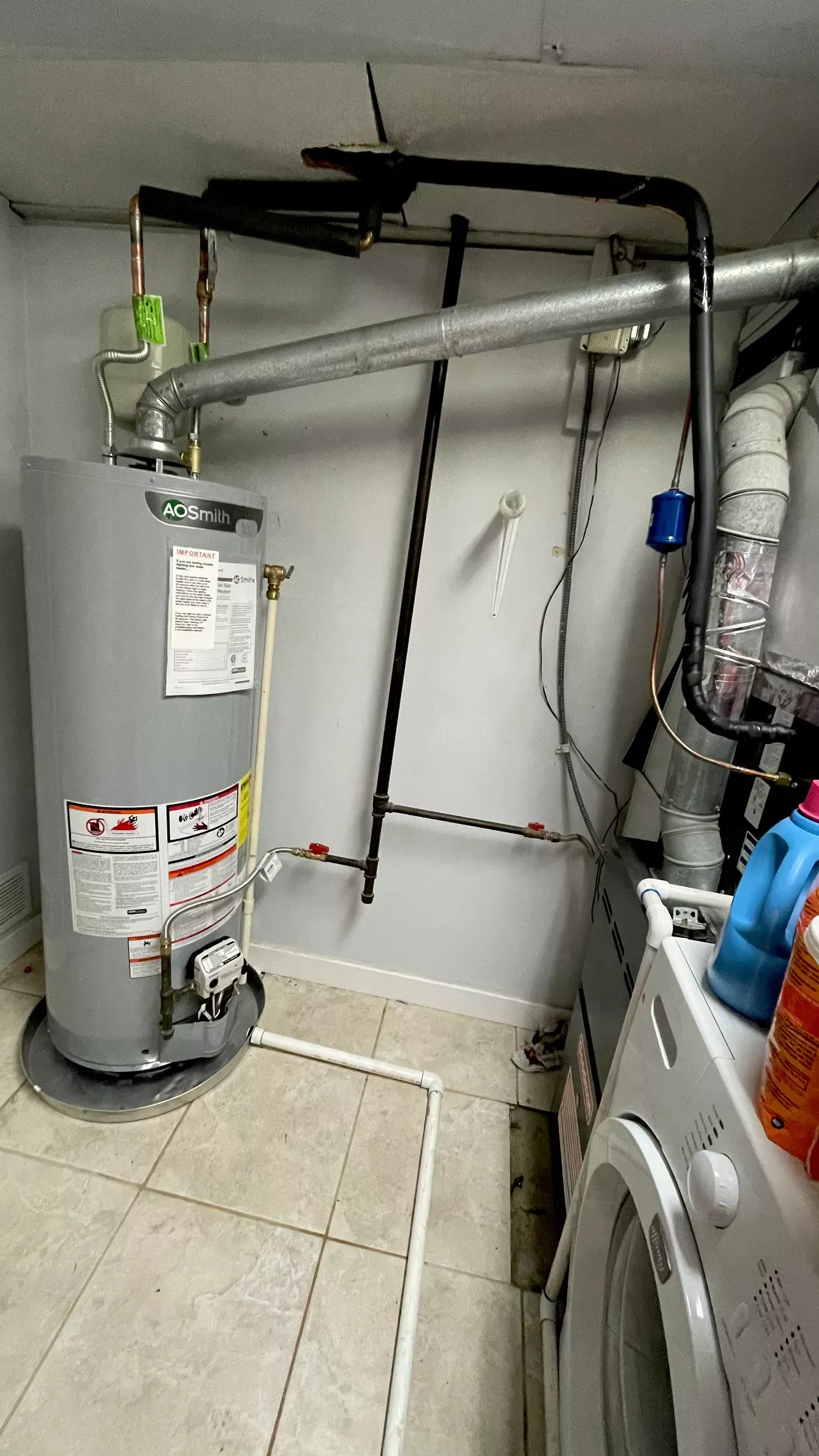 A laundry room with a water heater and a washing machine.