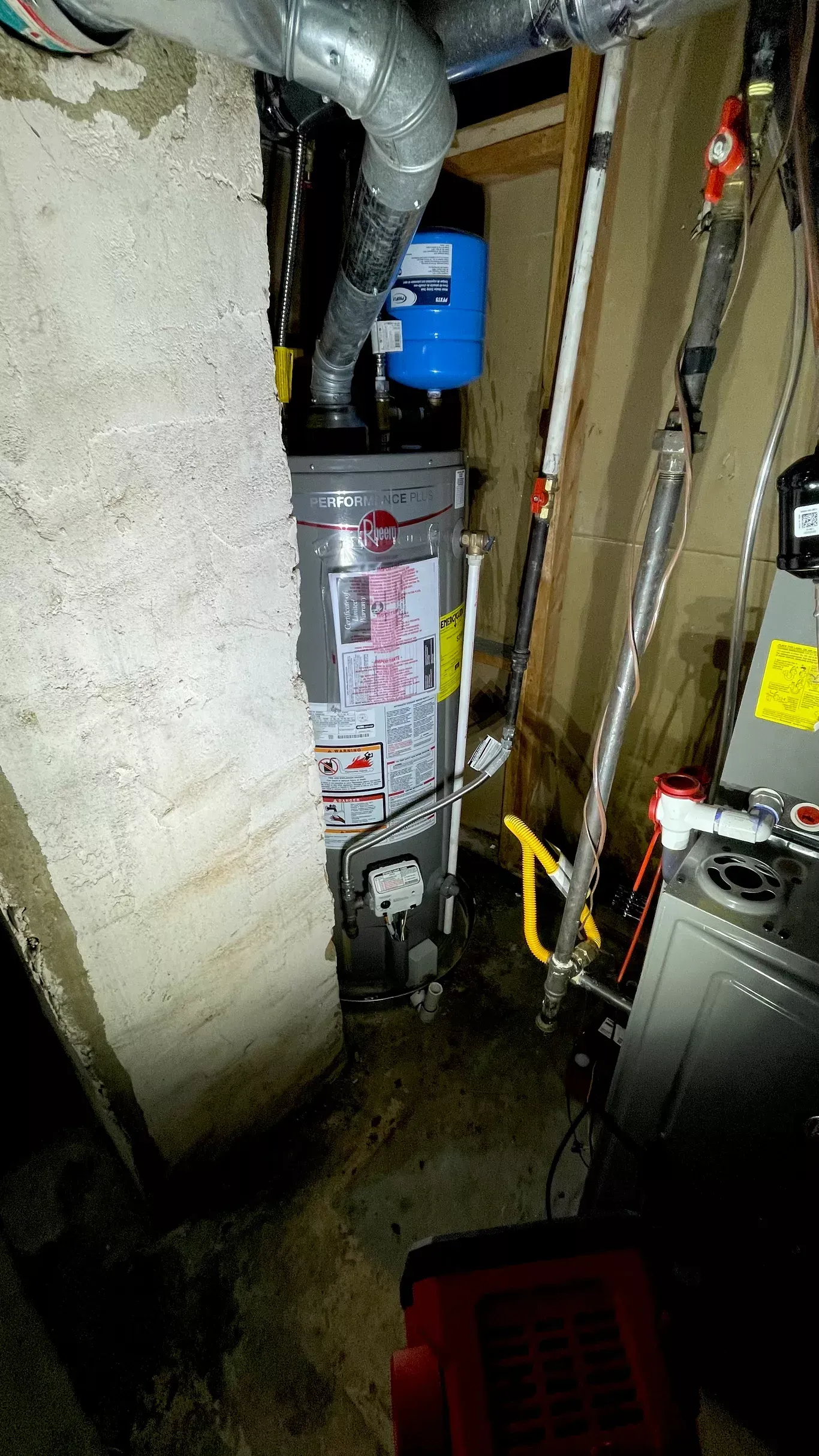 A furnace is sitting in a basement next to a wall.